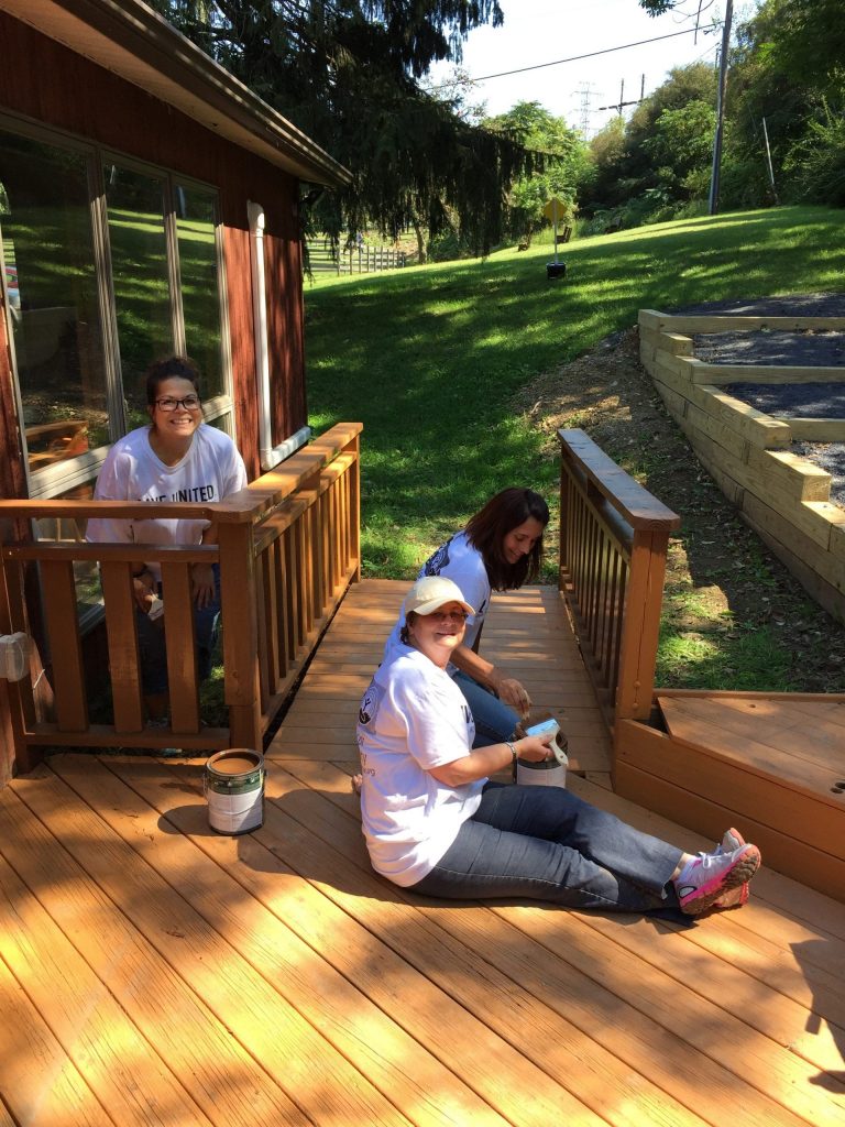 Day of caring team painting a deck 